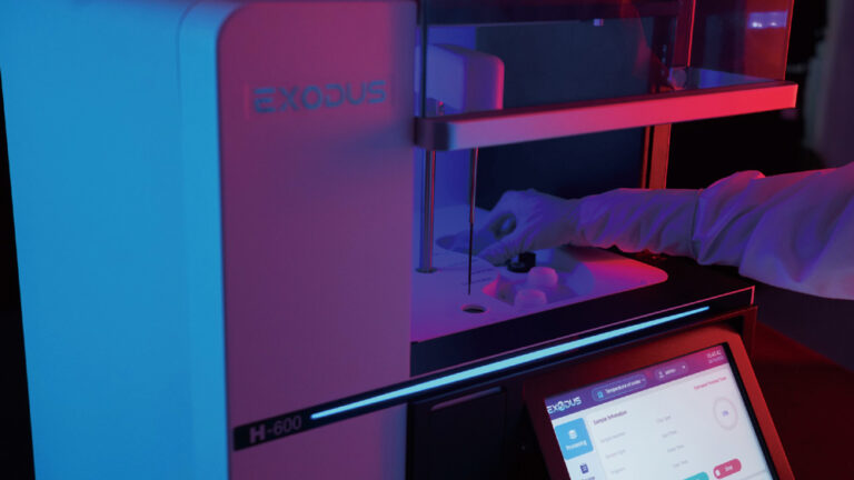 Operador carregando amostra biológica no reservatório do EXODUS H-600 (Step 1), com interface touchscreen ao fundo exibindo informações do processo.